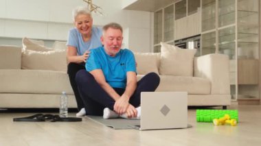 Yoga farkındalığı meditasyonu. Yetişkin bir çift olarak laptopta yoga yapıyoruz. Yaşlı kadın kocaya meditasyon yapmayı öğretiyor. Aile evde nefes egzersizi yapıyor.