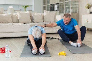 Fitness antrenmanı. Yetişkin, sağlıklı, yaşlı bir çift evde yoga minderinde spor yapıyor. Orta yaşlı koca karısı antrenman yapıyor. Sağlık hizmetleri sağlıklı yaşam tarzı