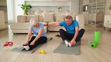 Fitness antrenmanı. Yetişkin, sağlıklı, yaşlı bir çift evde yoga minderinde spor yapıyor. Orta yaşlı koca karısı antrenman yapıyor. Sağlık hizmetleri sağlıklı yaşam tarzı