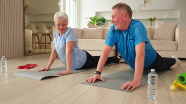 Fitness antrenmanı. Yetişkin, sağlıklı, yaşlı bir çift evde yoga minderinde spor yapıyor. Orta yaşlı koca karısı antrenman yapıyor. Sağlık hizmetleri sağlıklı yaşam tarzı