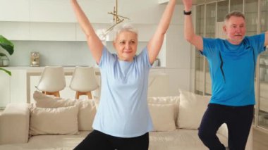 Fitness antrenmanı. Yetişkin, sağlıklı, yaşlı bir çift evde yoga minderinde spor yapıyor. Orta yaşlı bir kadın antrenman yapıyor. Sağlık hizmetleri sağlıklı yaşam tarzı