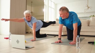 Fitness antrenmanı. Yetişkin, sağlıklı, yaşlı bir çift evde yoga minderinde spor yapıyor. Orta yaşlı koca karısı antrenman yapıyor. Sağlık hizmetleri sağlıklı yaşam tarzı