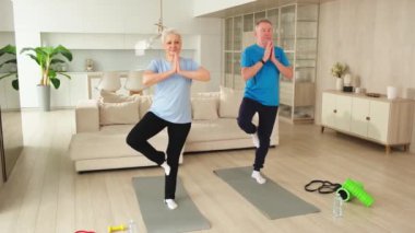 Fitness antrenmanı. Yetişkin, sağlıklı, yaşlı bir çift evde yoga minderinde spor yapıyor. Orta yaşlı bir kadın antrenman yapıyor. Sağlık hizmetleri sağlıklı yaşam tarzı