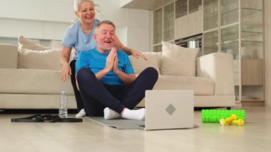 Yoga farkındalığı meditasyonu. Yetişkin bir çift olarak laptopta yoga yapıyoruz. Yaşlı kadın kocaya meditasyon yapmayı öğretiyor. Aile evde nefes egzersizi yapıyor.