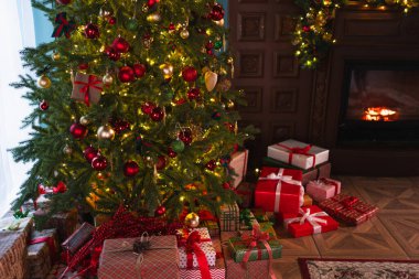 Klasik Noel dekore edilmiş şömineli oturma odası. Kırmızı altın süslemeli Noel ağacı hediye kutuları. Modern klasik iç tasarım dairesi. Evde Noel arifesi