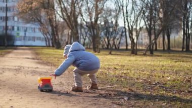 Mutlu bebek dışarıda. Oyuncak arabalı küçük çocuk parkta eğleniyor. Küçük oğlum dışarıda oynarken gülümsüyor. Küçük çocuk doğada dinleniyor. Küçük çocuk yürüyüş yaparken eğleniyor.