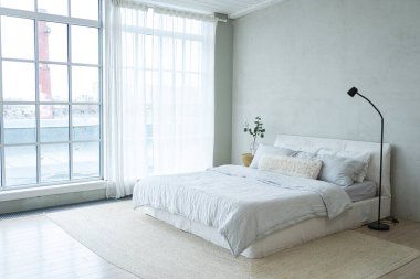 Evin içinde şık bir çatı katı var. Geniş duvarları, geniş pencereleri, büyük yatağı olan geniş bir tasarım dairesi. Minimalist İskandinav tarzında zarif mobilyalarla temiz modern dekorasyon.