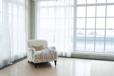 Kaliteli bir çatı katı. Geniş duvarları, geniş pencereleri, beyaz koltuğu olan geniş bir tasarım dairesi. Minimalist İskandinav tarzında zarif mobilyalarla temiz modern dekorasyon.