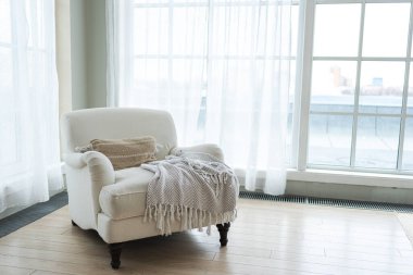 Kaliteli bir çatı katı. Geniş duvarları, geniş pencereleri, beyaz koltuğu olan geniş bir tasarım dairesi. Minimalist İskandinav tarzında zarif mobilyalarla temiz modern dekorasyon.