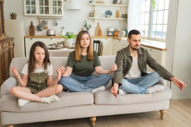 Yoga farkındalığı meditasyon duygusal refah. Evde yoga yapan mutlu bir aile. Anne, baba, kız, Lotus 'ta oturup meditasyon yapıyor. Aile, birlikte nefes alma egzersizi yapıyor.