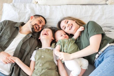 Evde mutlu bir aile. Anne baba, iki kız çocuk evde dinleniyor. Anne, baba, çocuklar kızlar sarılıp eğlenmek için rahatlar. Gülümseyen aile, şefkatli anların tadını çıkarıyor