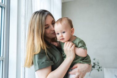 Evde mutlu bir aile. Anne kucağında küçük bir kız çocuğu. Anne ve bebek evde birlikte oynayarak rahatlar. Anne bebeğe sevgiyle sarılıyor. Bebeği emziren anne.