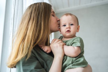 Evde mutlu bir aile. Anne kucağında küçük bir kız çocuğu. Anne ve bebek evde birlikte oynayarak rahatlar. Anne bebeğe sevgiyle sarılıyor. Bebeği emziren anne.