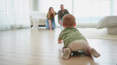 Mutlu bir aile. Anne baba yatak odasında yerde sürünen tatlı küçük kıza bakıyor. Bebek dinleniyor, evde ebeveynlerle oynuyor. Anne, baba, yeni doğan bebek. Tatlı sürünen çocuk.
