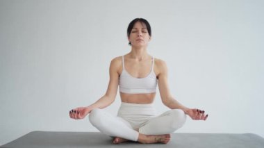 Yoga farkındalığı meditasyonu. Sağlıklı bir kadın beyaz arka planda izole edilmiş yoga yapıyor. Lotus 'ta oturan kadın meditasyon yapıyor. Nefes egzersizi yapan bir kız. Beyaz arkaplanda yoga