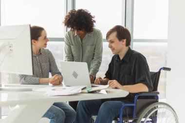 Takım çalışması beyin fırtınası. Çeşitli çok ırklı meslektaşlar birlikte çalışan engelli insanlar için sandalyede oturuyor. Yaratıcı ofiste oturup iş konuşan bir grup insan. Genç profesyonel takım