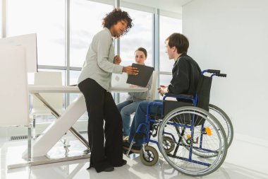 Takım çalışması beyin fırtınası. Çeşitli çok ırklı meslektaşlar birlikte çalışan engelli insanlar için sandalyede oturuyor. Yaratıcı ofiste oturup iş konuşan bir grup insan. Genç profesyonel takım