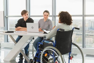 Takım çalışması beyin fırtınası. Çeşitli çok ırklı iş arkadaşları olan kadın engelliler için birlikte çalışıyor. Yaratıcı ofiste oturup iş konuşan bir grup insan. Genç profesyonel takım