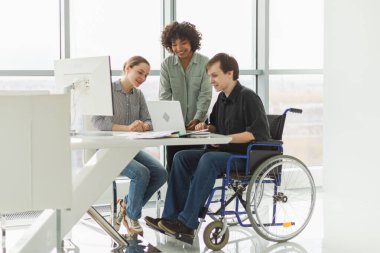 Takım çalışması beyin fırtınası. Çeşitli çok ırklı meslektaşlar birlikte çalışan engelli insanlar için sandalyede oturuyor. Yaratıcı ofiste oturup iş konuşan bir grup insan. Genç profesyonel takım