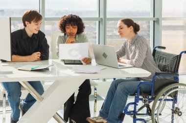 Takım çalışması beyin fırtınası. Çeşitli çok ırklı iş arkadaşları olan kadın engelliler için birlikte çalışıyor. Yaratıcı ofiste oturup iş konuşan bir grup insan. Genç profesyonel takım