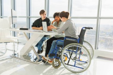 Takım çalışması beyin fırtınası. Çeşitli çok ırklı iş arkadaşları olan kadın engelliler için birlikte çalışıyor. Yaratıcı ofiste oturup iş konuşan bir grup insan. Genç profesyonel takım