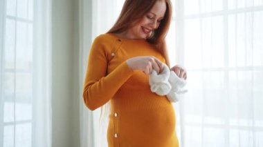 Hamilelik anneliği insanların gelecek beklentisi. Koca göbekli hamile bir kadın kucağında bebek poposu ile evde gülümsüyor. Genç anne hamileliğin tadını çıkarıyor. Annelik şefkati ebeveynlik yeni bir hayat