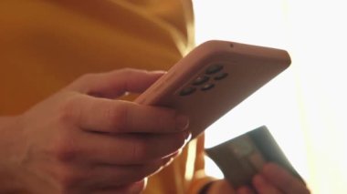 Kadının biri elinde akıllı telefonuyla alışveriş yapıyor ve kredi kartıyla ödeme yapıyor. İnternetten alışveriş yapan kızlar kredi kartı bilgilerini girerler. Çevrimiçi alışveriş ekommerce dağıtım servisi