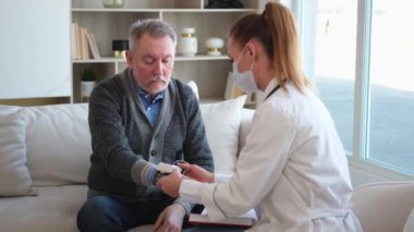 Doktor muayenehanesinde ya da evde tansiyonunu ölçen yaşlı bayan doktor. Yaşlı hasta ve doktorun hastane odasında muayeneleri var. Tıbbi sağlık hizmetleri sağlık kontrolü. Doktoru ziyaret et.