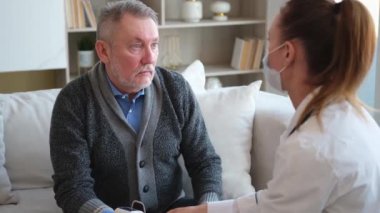 Doktor muayenehanesinde ya da evde yaşlı bir adamı muayene eden kadın doktor. Yaşlı hasta ve doktorun hastane odasında muayeneleri var. Tıbbi sağlık hizmetleri sağlık kontrolü. Doktoru ziyaret et.