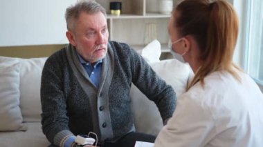 Doktor muayenehanesinde ya da evde tansiyonunu ölçen yaşlı bayan doktor. Yaşlı hasta ve doktorun hastane odasında muayeneleri var. Tıbbi sağlık hizmetleri sağlık kontrolü. Doktoru ziyaret et.