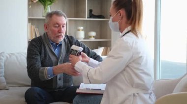 Doktor muayenehanesinde ya da evde tansiyonunu ölçen yaşlı bayan doktor. Yaşlı hasta ve doktorun hastane odasında muayeneleri var. Tıbbi sağlık hizmetleri sağlık kontrolü. Doktoru ziyaret et.