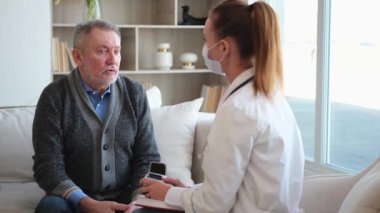 Doktor muayenehanesinde ya da evde yaşlı bir adamı muayene eden kadın doktor. Yaşlı hasta ve doktorun hastane odasında muayeneleri var. Tıbbi sağlık hizmetleri sağlık kontrolü. Doktoru ziyaret et.