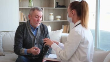 Doktor muayenehanesinde ya da evde yaşlı bir adamı muayene eden kadın doktor. Yaşlı hasta ve doktorun hastane odasında muayeneleri var. Tıbbi sağlık hizmetleri sağlık kontrolü. Doktoru ziyaret et.