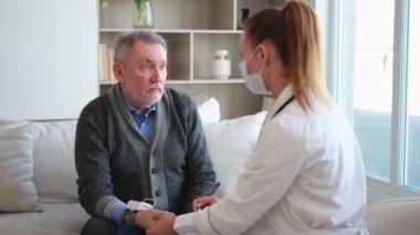 Doktor muayenehanesinde ya da evde yaşlı bir adamı muayene eden kadın doktor. Yaşlı hasta ve doktorun hastane odasında muayeneleri var. Tıbbi sağlık hizmetleri sağlık kontrolü. Doktoru ziyaret et.