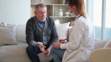 Doktor muayenehanesinde ya da evde yaşlı bir adamı muayene eden kadın doktor. Yaşlı hasta ve doktorun hastane odasında muayeneleri var. Tıbbi sağlık hizmetleri sağlık kontrolü. Doktoru ziyaret et.