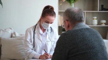 Doktor muayenehanesinde ya da evde yaşlı bir adamı muayene eden kadın doktor. Yaşlı hasta ve doktorun hastane odasında muayeneleri var. Tıbbi sağlık hizmetleri sağlık kontrolü. Doktoru ziyaret et.