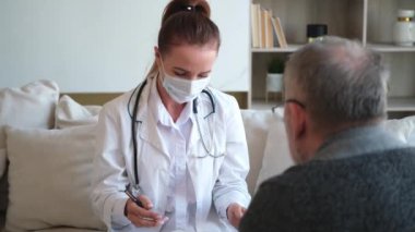 Doktor muayenehanesinde ya da evde yaşlı bir adamı muayene eden kadın doktor. Yaşlı hasta ve doktorun hastane odasında muayeneleri var. Tıbbi sağlık hizmetleri sağlık kontrolü. Doktoru ziyaret et.