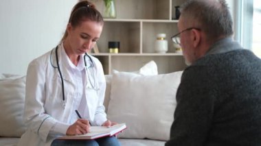 Doktor muayenehanesinde ya da evde yaşlı bir adamı muayene eden kadın doktor. Yaşlı hasta ve doktorun hastane odasında muayeneleri var. Tıbbi sağlık hizmetleri sağlık kontrolü. Doktoru ziyaret et.