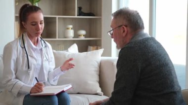 Doktor muayenehanesinde ya da evde yaşlı bir adamı muayene eden kadın doktor. Yaşlı hasta ve doktorun hastane odasında muayeneleri var. Tıbbi sağlık hizmetleri sağlık kontrolü. Doktoru ziyaret et.