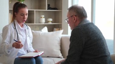 Doktor muayenehanesinde ya da evde yaşlı bir adamı muayene eden kadın doktor. Yaşlı hasta ve doktorun hastane odasında muayeneleri var. Tıbbi sağlık hizmetleri sağlık kontrolü. Doktoru ziyaret et.