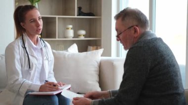 Doktor muayenehanesinde ya da evde yaşlı bir adamı muayene eden kadın doktor. Yaşlı hasta ve doktorun hastane odasında muayeneleri var. Tıbbi sağlık hizmetleri sağlık kontrolü. Doktoru ziyaret et.