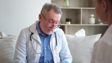 Kıdemli doktor, genç bayanı muayenehanede ya da evde muayene ediyor. Kız hasta ve doktorun hastane odasında muayenesi var. Tıbbi sağlık hizmetleri sağlık kontrolü. Doktoru ziyaret et.