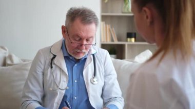 Kıdemli doktor, genç bayanı muayenehanede ya da evde muayene ediyor. Kız hasta ve doktorun hastane odasında muayenesi var. Tıbbi sağlık hizmetleri sağlık kontrolü. Doktoru ziyaret et.