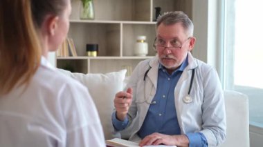 Kıdemli doktor, genç bayanı muayenehanede ya da evde muayene ediyor. Kız hasta ve doktorun hastane odasında muayenesi var. Tıbbi sağlık hizmetleri sağlık kontrolü. Doktoru ziyaret et.