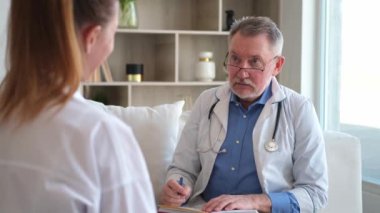 Kıdemli doktor, genç bayanı muayenehanede ya da evde muayene ediyor. Kız hasta ve doktorun hastane odasında muayenesi var. Tıbbi sağlık hizmetleri sağlık kontrolü. Doktoru ziyaret et.