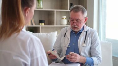 Kıdemli doktor, genç bayanı muayenehanede ya da evde muayene ediyor. Kız hasta ve doktorun hastane odasında muayenesi var. Tıbbi sağlık hizmetleri sağlık kontrolü. Doktoru ziyaret et.