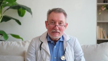 Üst düzey doktor görüntülü konuşma yapıyor. Hasta ile görüş alışverişinde bulunun. Kamera kamerasına bakın. Profesyonel yetişkin sağlık uzmanı hastayı internetten muayene ediyor. Sağlık sigortası konsepti. Web kamerası görünümü