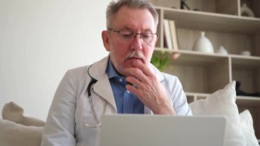 Dizüstü bilgisayarla çalışan kıdemli doktor. Profesyonel yetişkin sağlık uzmanı bilgi arıyor ya da hastane odasında online danışmanlık yapıyor. Tıbbi sağlık hizmetleri sağlık kontrolü