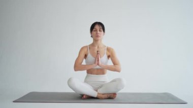 Yoga farkındalığı meditasyonu. Sağlıklı bir kadın beyaz arka planda izole edilmiş yoga yapıyor. Lotus 'ta oturan kadın meditasyon yapıyor. Nefes egzersizi yapan bir kız. Beyaz arkaplanda yoga
