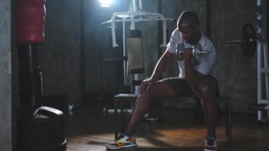 Beden eğitiminde spor. Spor salonunda dambılları toplayan Afrikalı Amerikalı bir vücut geliştirici. Fitness kulübünde halterli kasları çalıştırmak için ağırlık çalışıyorum. Spor yapan bir adam. Sağlıklı yaşam tarzı